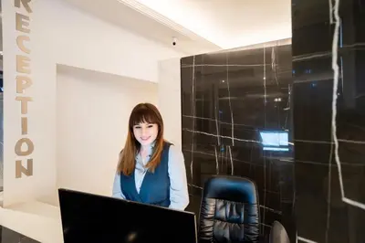 a woman sitting in front of a laptop computer at Hotel Alexandar Lux in Podgorica