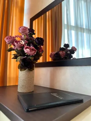a vase of flowers on a table in front of a mirror at Hotel Alexandar Lux in Podgorica