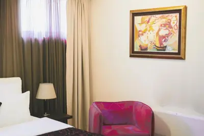 a bed and a chair in a hotel room at Hotel Alexandar Lux in Podgorica