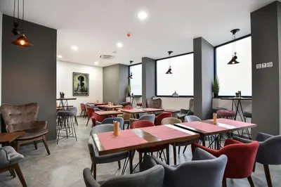 a restaurant with tables and chairs and windows at Perla Residence Hotel & SPA in Podgorica