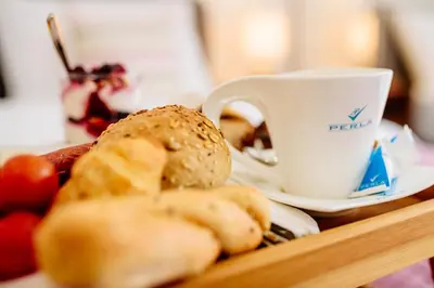 a tray of food with a cup of coffee and bread at Perla Residence Hotel & SPA in Podgorica