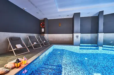 a large swimming pool with blue tiles in a hotel room at Perla Residence Hotel & SPA in Podgorica