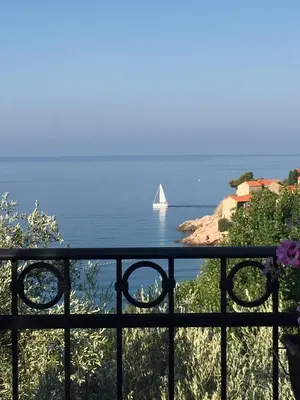 a white sailboat in the water with a ship at Monte Perla Residence in Sveti Stefan