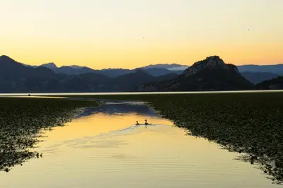 two people on a boat in a river at sunset at Vida`s house in Virpazar