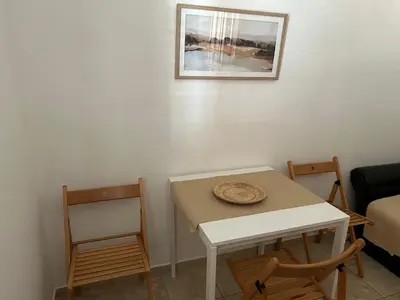a table and chairs in a room with a picture on the wall at Apartments Djulija in Sutomore