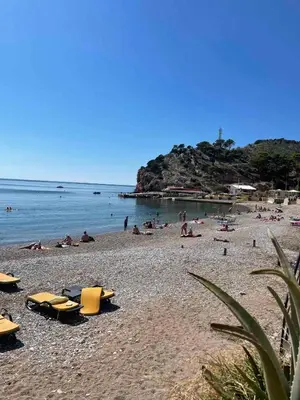 a beach with yellow chairs and people in the water at Apartments Djulija in Sutomore