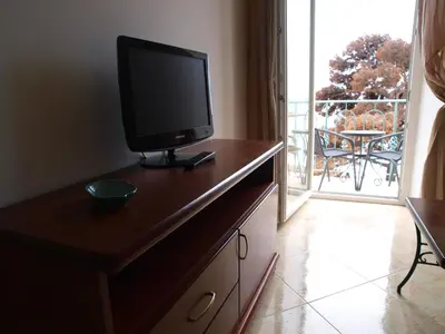 a television on a dresser in a room with a balcony at Apartments Obala B&B - Dragović in Petrovac na Moru