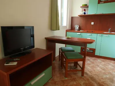 a kitchen with a tv and a table with a chair at Apartments Laništa - Dragović in Petrovac na Moru
