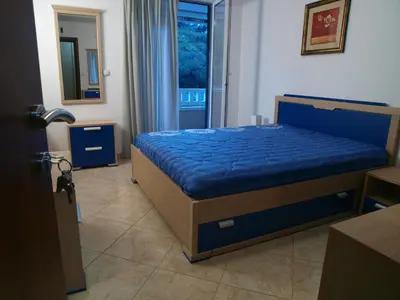 a bedroom with a bed with blue sheets and a window at Apartments Laništa - Dragović in Petrovac na Moru