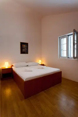 a bedroom with a large bed with two lamps on it at Apartments Kovinic in Tivat