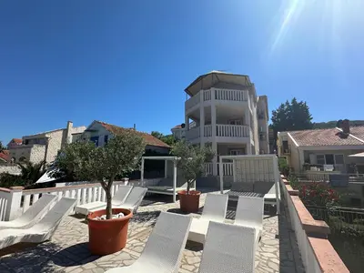 a group of white chairs on a patio in front of a house at Apartments Kovinic in Tivat