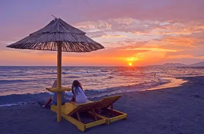a woman sitting on a chair under an umbrella on the beach at Cozy studio by the sea in Ulcinj, 35 m² with view in Ulcinj