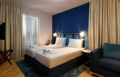 a hotel room with a large bed and a chair at Panonija in Kotor