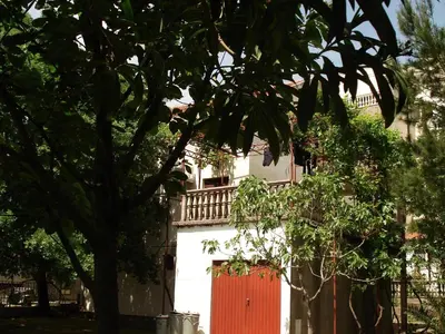 a white building with a red door and trees at Apartments Aleksic in Sutomore