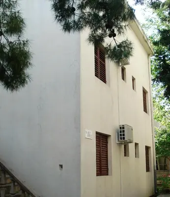 a white building with brown shuttered windows at Apartments Aleksic in Sutomore