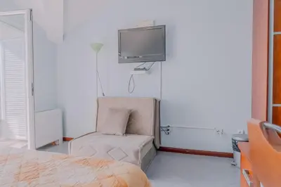 a bedroom with a chair and a tv on the wall at Hotel R in Utjeha