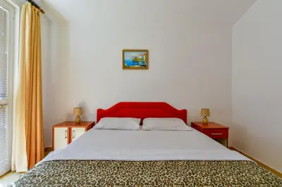 a bedroom with a bed with a red headboard at Rooms and Apartments Oregon in Budva