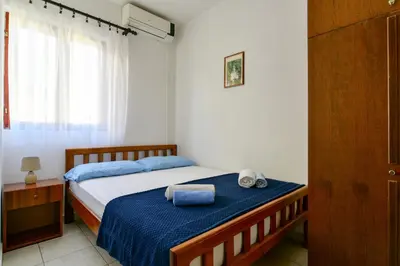 a bedroom with a bed with blue sheets and a window at Rooms and Apartments Oregon in Budva