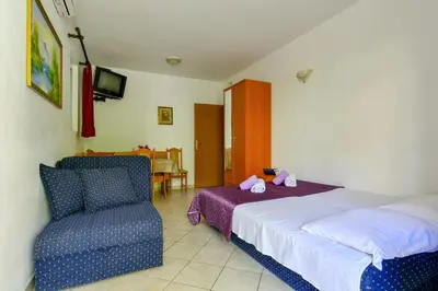 a bedroom with a bed and a chair at Rooms and Apartments Oregon in Budva