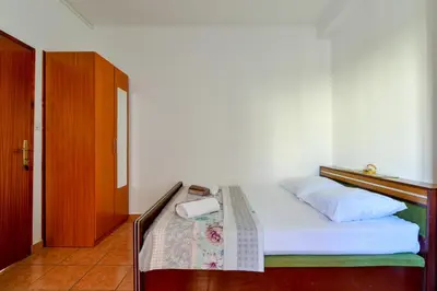a bedroom with a bed with a wooden headboard at Rooms and Apartments Oregon in Budva
