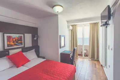 a hotel room with a red bed and a window at David apartments and rooms in Dobra Voda