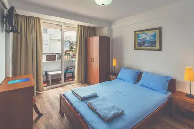a bedroom with a blue bed with a desk and a window at David apartments and rooms in Dobra Voda