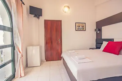 a bedroom with a bed with a red pillow and a door at David apartments and rooms in Dobra Voda