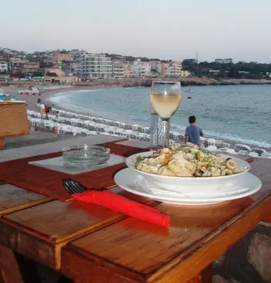 a table with a plate of food and a glass of wine at David apartments and rooms in Dobra Voda