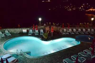 a swimming pool at night with chairs and tables at David apartments and rooms in Dobra Voda