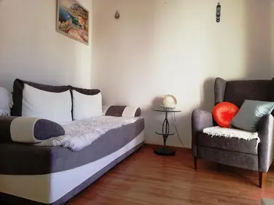 a bedroom with a bed and a couch and a chair at Apartment White Lily of Budva in Budva