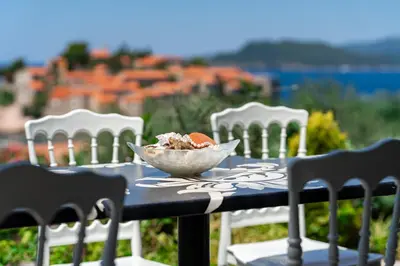 a bowl of food sitting on a table with chairs at Sun Rose Apartments Sveti Stefan in Sveti Stefan
