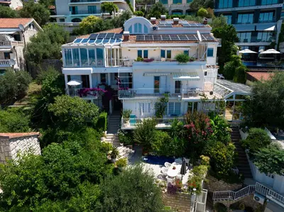 a white house with solar panels on its roof at Sun Rose Apartments Sveti Stefan in Sveti Stefan