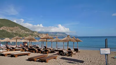 a beach with chairs and umbrellas and the ocean at MM Apartments in Budva