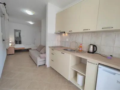 a kitchen with white cabinets and a couch in a room at MM Apartments in Budva