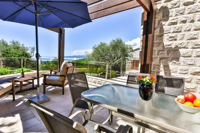 a patio with a table and chairs and an umbrella at Villa Rijeka Rezevici in Petrovac na Moru