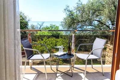 a balcony with two chairs and a table with a bottle of wine at Villa Rijeka Rezevici in Petrovac na Moru