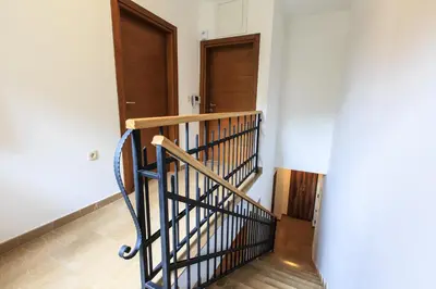 a hallway with two wooden doors and a staircase at Villa Rijeka Rezevici in Petrovac na Moru