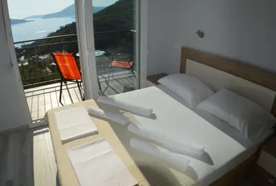 a bedroom with a bed and a balcony with a view at Apartments MM in Sveti Stefan