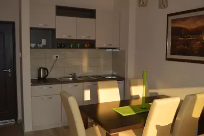 a kitchen with a wooden table and a dining room at Apartments MM in Sveti Stefan