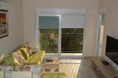 a living room with a couch and a large window at Apartments MM in Sveti Stefan