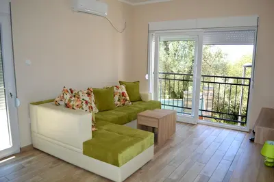a living room with a green couch and a balcony at Apartments MM in Sveti Stefan