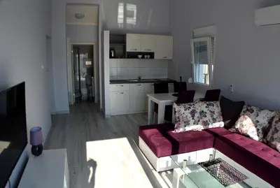 a living room with a red couch and a kitchen at Apartments MM in Sveti Stefan