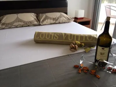a bottle of wine sitting on a bed with a bottle of wine at Apartments Perezaj II in Ulcinj