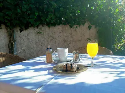 a table with a plate of food and a glass of orange juice at Hotel Laguna in Podgorica