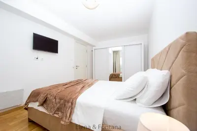 a white bedroom with a large bed with white pillows at Elena&Fontana Apartment in Budva