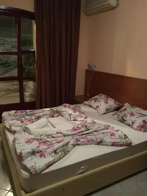 an unmade bed with pink flowers on it with a window at Apartments Mara in Budva