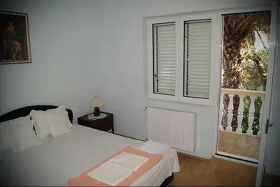 a white bedroom with a bed and a window at Guest House Ratko in Rafailovici