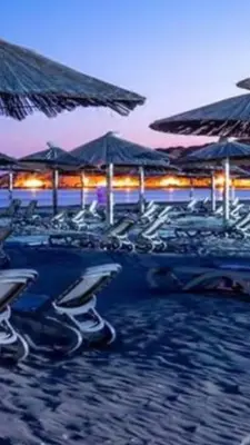 a group of chairs and umbrellas on a beach at Apartments Vila Sara M in Ulcinj