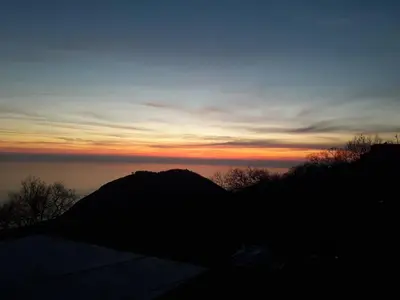 a sunset over the ocean with a mountain in the foreground at House Stijepovic in Petrovac na Moru