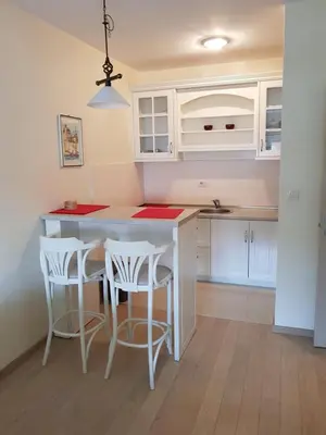 a kitchen with white cabinets and a table with stools at Apartments City Life in Podgorica